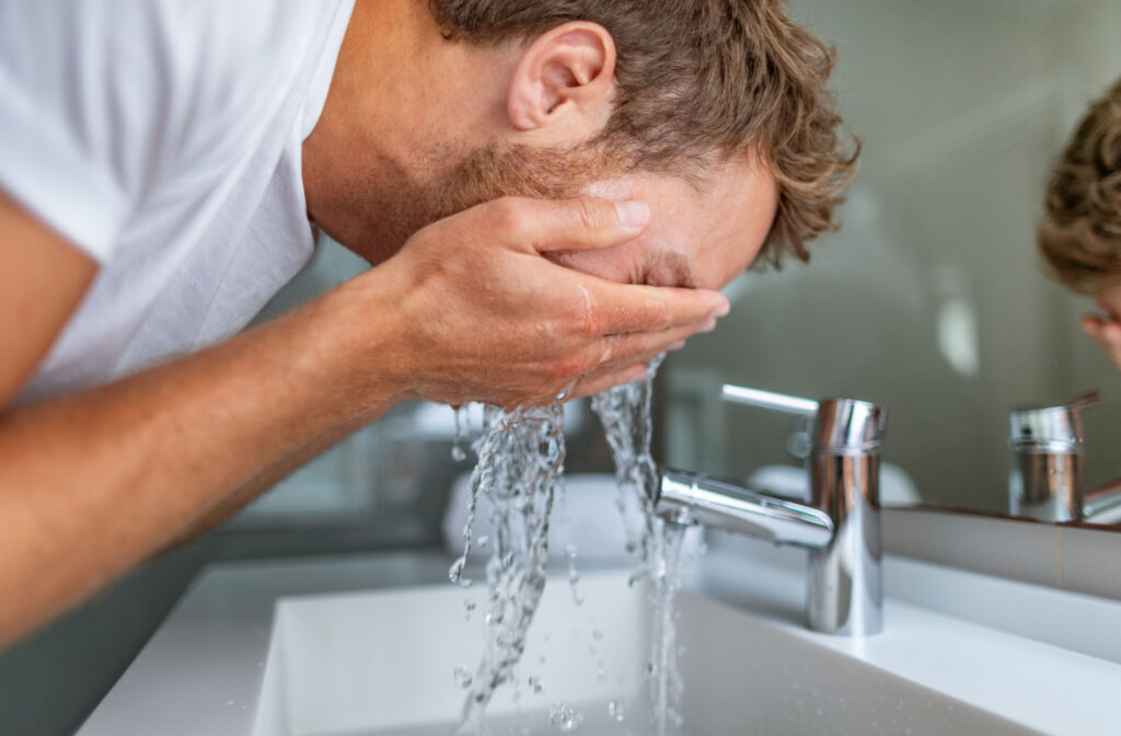 A man rinsing his eyes to dislodge the eyelash on his eye.