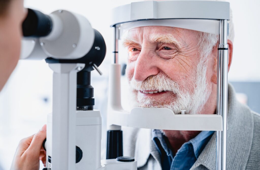 A senior man smiling during an eye exam while his optometrist determines if he qualifies for LASIK.