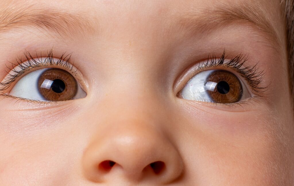 A young toddler with warm brown eyes looks off to the side of the camera.