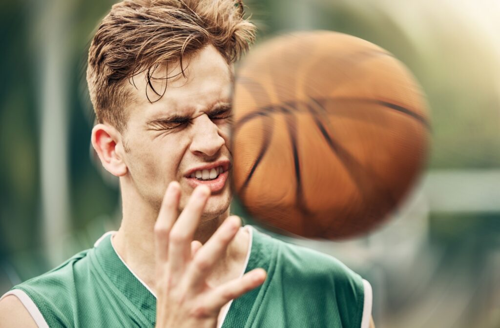 An image of a basketball hitting the left side of an athlete's face and head.