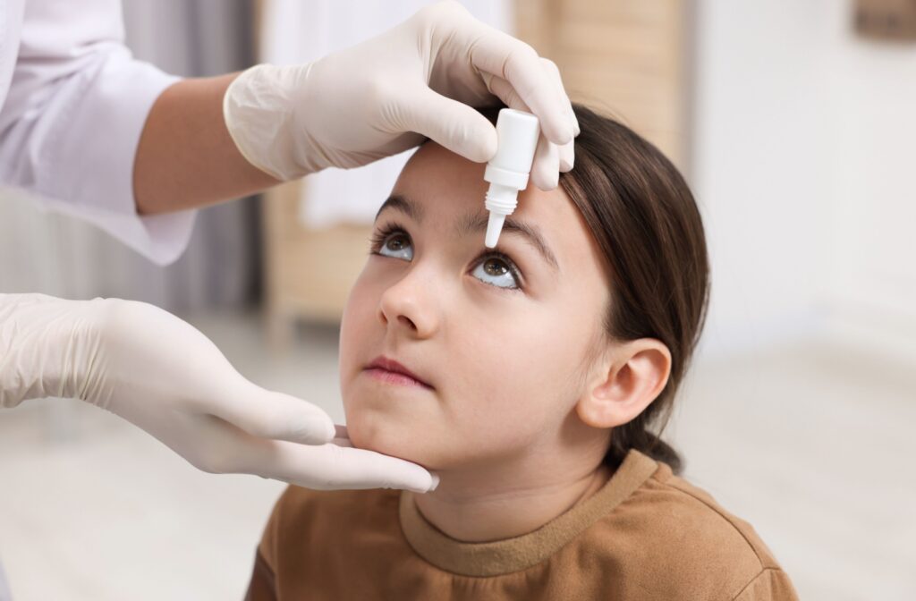 An adult administering kids eyes drops.
